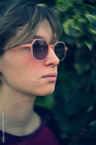 Vertical swallow focus shot of young female with pink sunglasses
