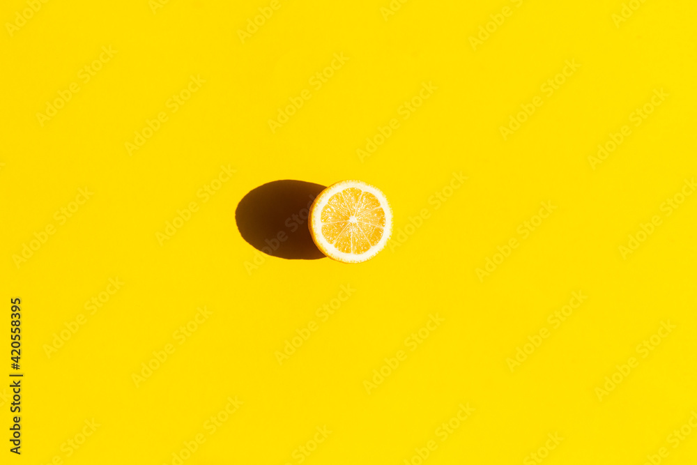 Fototapeta Fresh lemon cut in half, isolated on yellow background, flat lay.