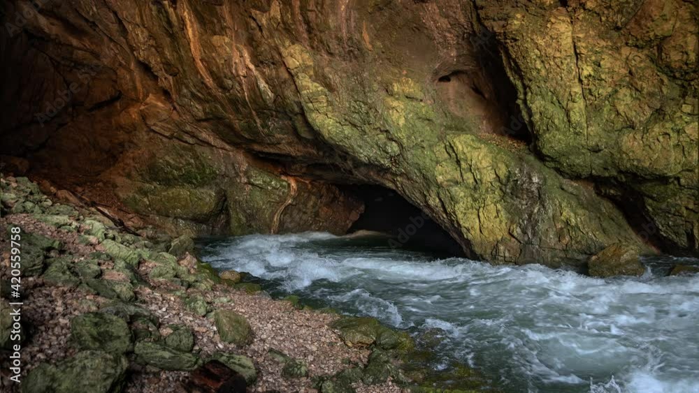 Wild river Rak flowing in Weaver Cave entrance, Rakov Skocjan. Karst spring with clean and fresh water in Slovenia. Beautiful nature deep in underground. Static shot, real time, wide angle Wild river Rak flowing in Weaver Cave entrance, Rakov Skocjan. Karst spring with clean and fresh water in Slovenia. Beautiful nature deep in underground. Static shot, real time, wide angle