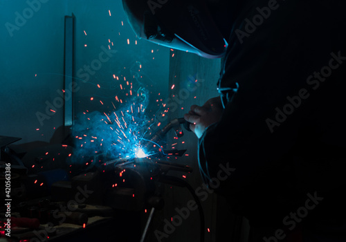 Foto Metallurgist welding a structure in a dark workshop