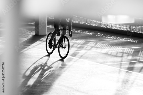 Cyclist Urban Bike Racer in car park environment, monochrome contrast light and shadows on ground silhouette photo