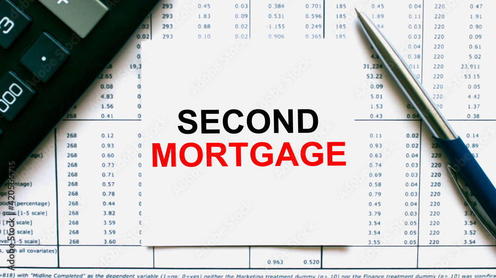 The business card with the text Second Mortgage is on the financial documents. Calculator and pen The business card with the text Second Mortgage is on the financial documents. Calculator and pen