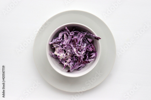 Easy homecooked creamy coleslaw from red cabbage in a bowl on white table background. Top view  copy space. Fresh vegetable salad with mayonnaise dressing. Flat lay food. Healthy eating concept 