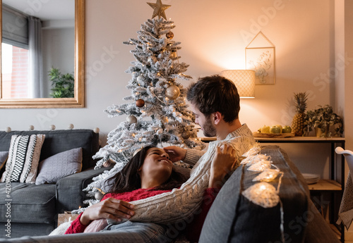 Happy diverse couple lounging on couch on Christmas eve photo