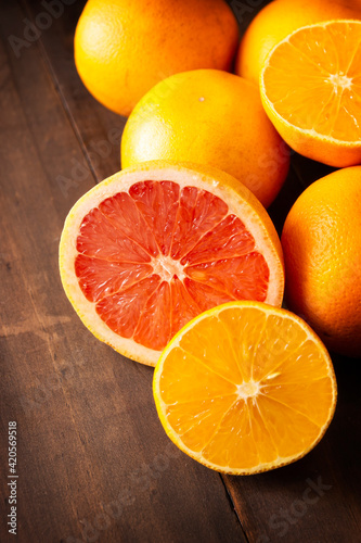 ripe orange and grapefruit slices and several whole oranges on brown rustic wooden table with copy space