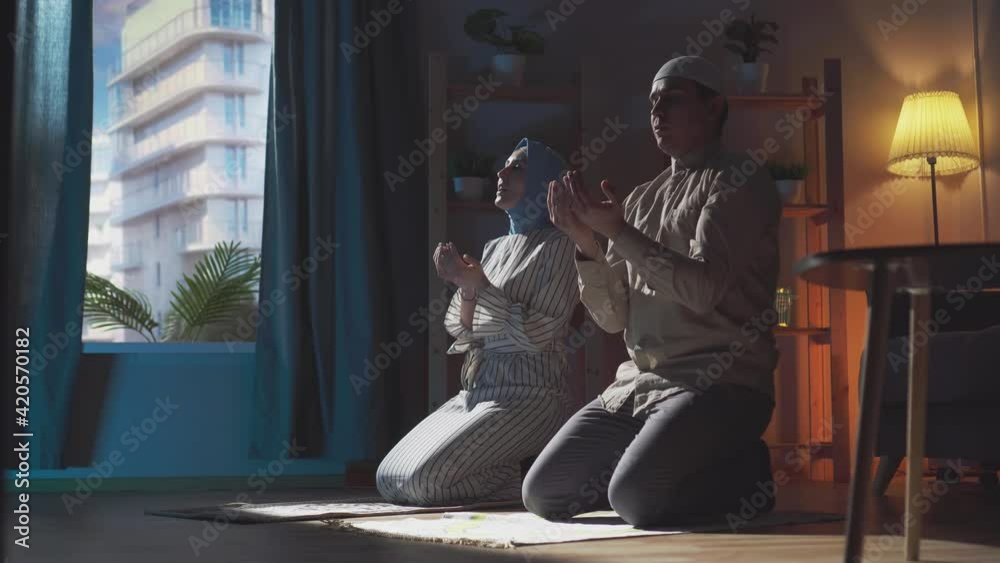 muslim couple joint prayer at home in traditional clothing