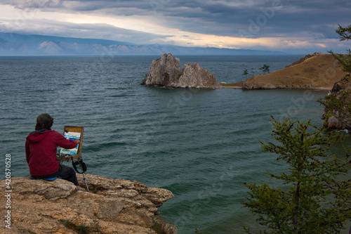 June 2015, Lake Baikal, Russia. The artist paints coastal rocks on the shore of the lake
