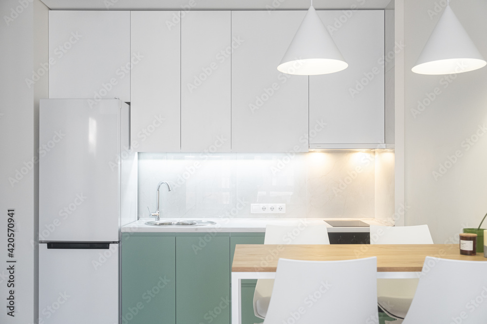 Modern kitchen with dining table and lights.