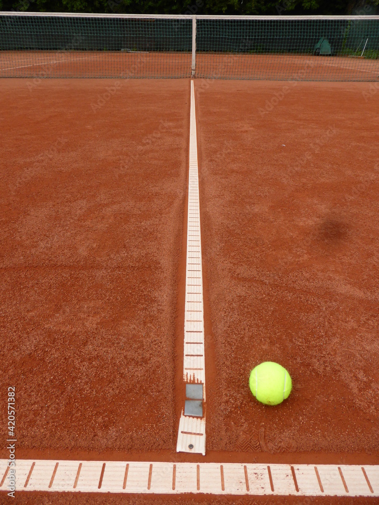 Tennisball im T-Feld eines Tennisplatzes liegend.