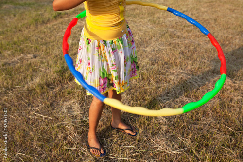 Teenage Girl Playing With Hula Hoop in a greenfield
