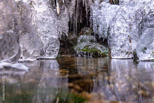 Waterfall in winter. Water jets freeze and icicles form. Attractive ice shapes and white frost - like a theater stage and impressive winter sets