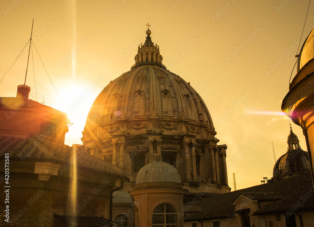 Dome, roof of St Peter in the Vatican, Rome, surrounded by the rays of the sun at sunset 