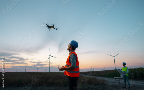 Drone operated by construction worker inspecting wind turbine