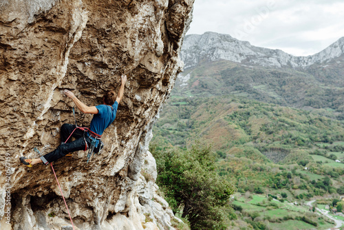 Young climber man climbing a steep overhanging wall