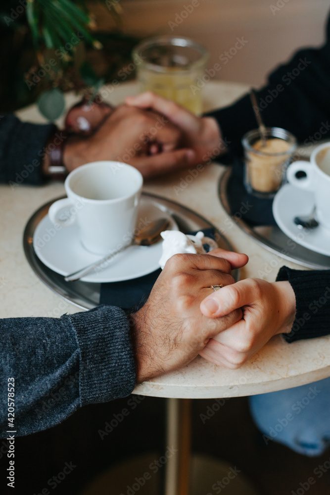 Interracial couple holding hands over a coffee table Interracial couple holding hands over a coffee table