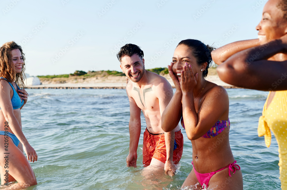 Friends standing in the ocean and laughing Friends standing in the ocean and laughing