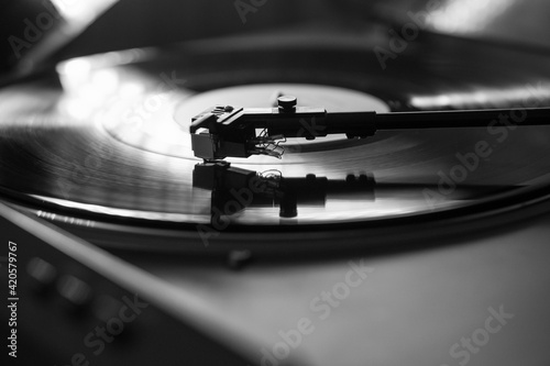 Closeup view of a tonearm and turntable playing vinyl record.