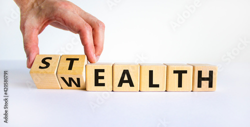 Stealth wealth symbol. Businessman turns wooden cubes and changes the word 'wealth' to 'stealth'. Beautiful white background. Business, stealth wealth concept. Copy space.