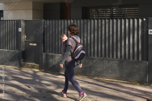 a woman carrying her child exercising in an urban environment © curto