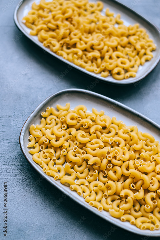 Wheat raw Italian pasta in plates isolated on blue background. Wheat raw Italian pasta in plates isolated on blue background.