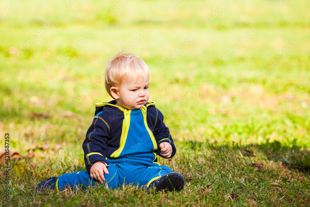 the sad baby is sitting on the lawn looking at the grass the sad baby is sitting on the lawn looking at the grass