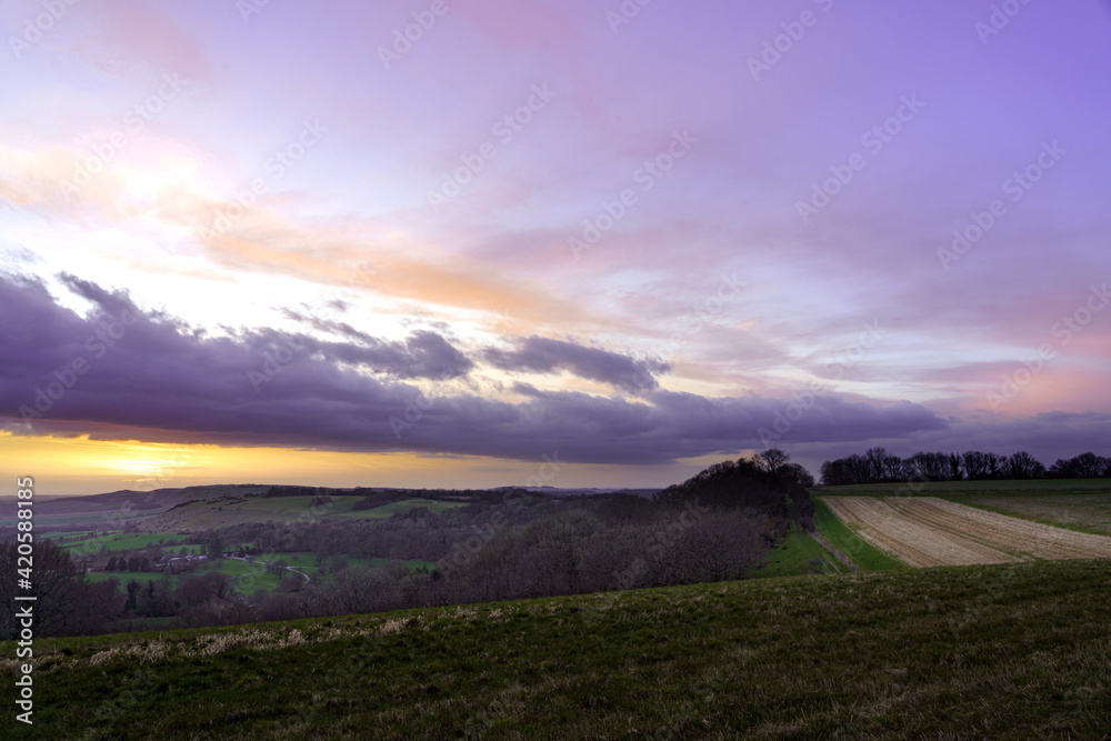 a dramatic sky and scenic Westerly view as the golden sun sets over Oare and across the Pewsey Vale valley AONB UK