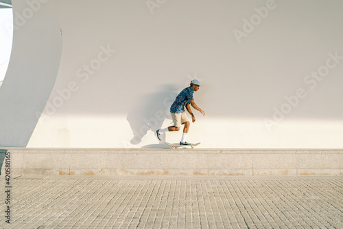 Ethnic skater riding skateboard on border photo