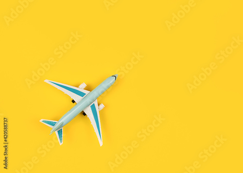 Miniature of a blue plane on a yellow background. Horizontal photo, flat lay. Space for text, copy space. Concept - air travel, ticket booking