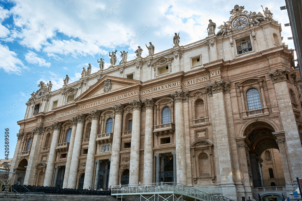 A view of the facade of St. Peter's Basilica at Saint Peter's Square in the Vatican City in Rome, Italy, under blue cloudy sky on a spring day.