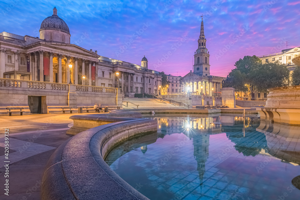 Night cityscape with a colourful, dramatic sky at sunrise or sunset at Trafalgar Square and the National Gallery in central London, UK.