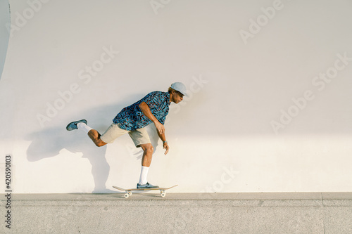 Ethnic skater riding skateboard on border