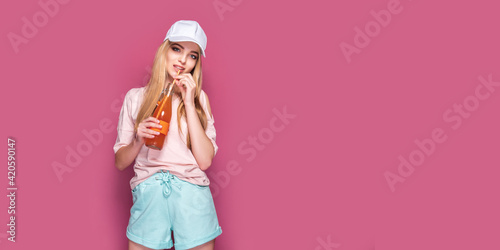 Sporty woman with cold drink standing on pink background
