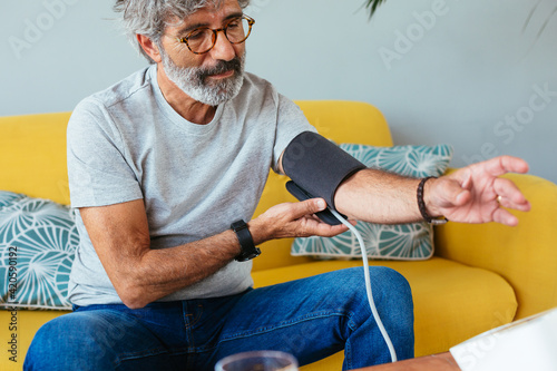 Senior man measuring blood pressure with device