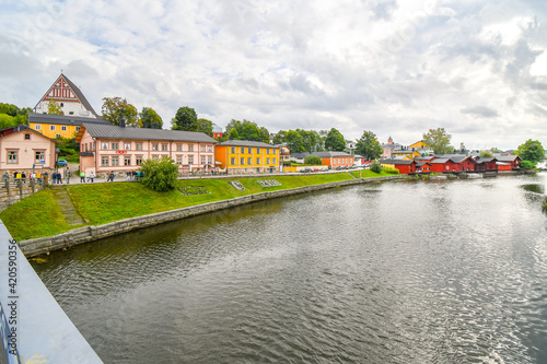 Tourists walk along the Porvoonjoki river adjacent to the medieval village and waterfront homes of Porvoo, Finland in early autumn