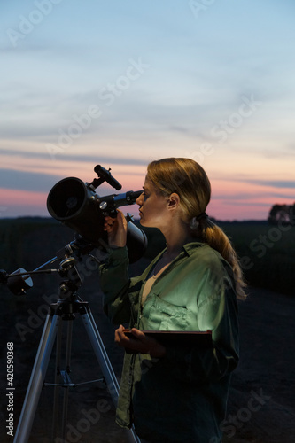 Female stargazer with tablet using telescope in evening photo