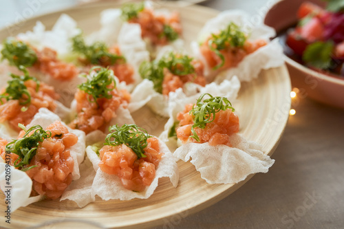 salmon tartare on rice chips with onion hay photo