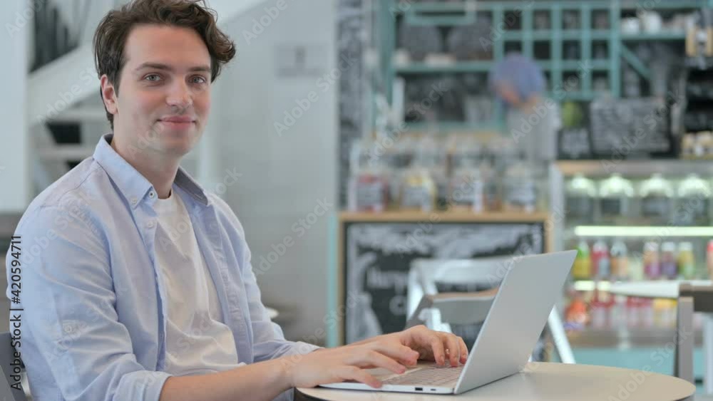 Young Man with Laptop Shaking Head as Yes Sign 
