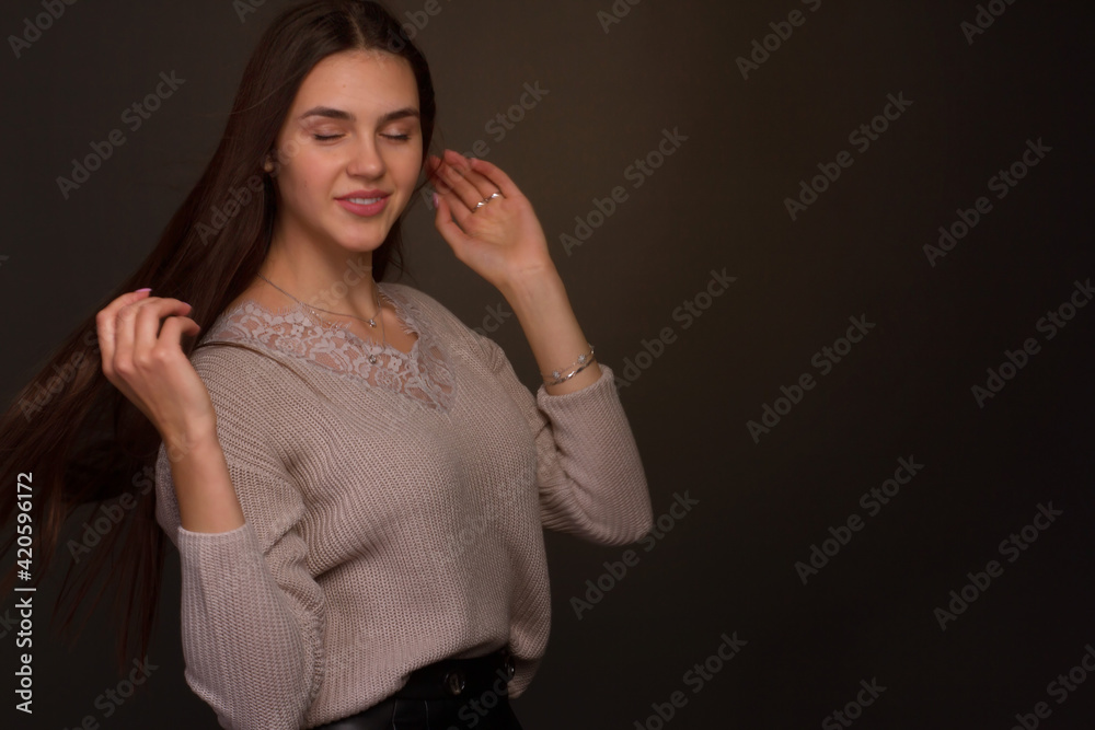 portrait of a young woman with long brown hair. In a beige blouse on a black background. portrait of a young woman with long brown hair. In a beige blouse on a black background.