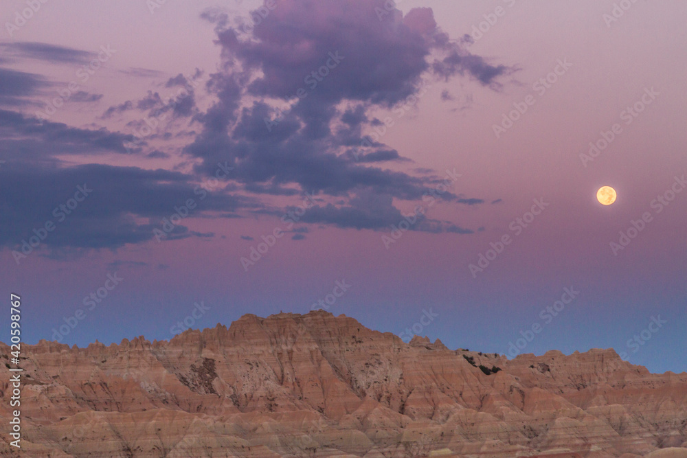 USA, South Dakota, Badlands National Park. Sunrise and moonset over rugged landscape.