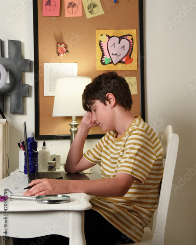 Boy Student Tired in front of Laptop Computer at Home