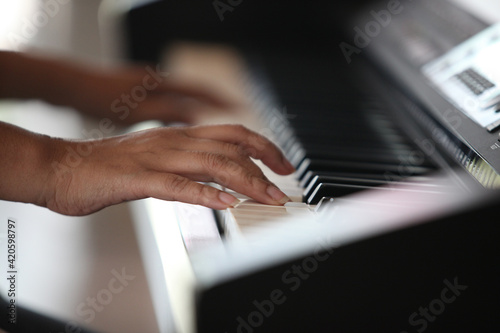Close-up of a music performer's hand playing the piano , Piano keyboard background with selective focus. Warm color toned image