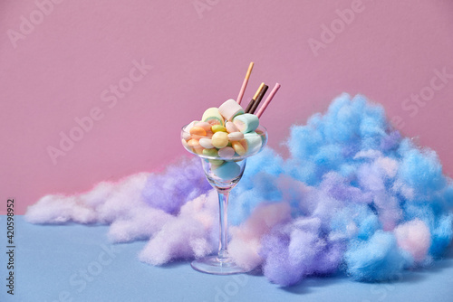 A glass of Iced strawberry shake and topped with cotton candy and marshmallow