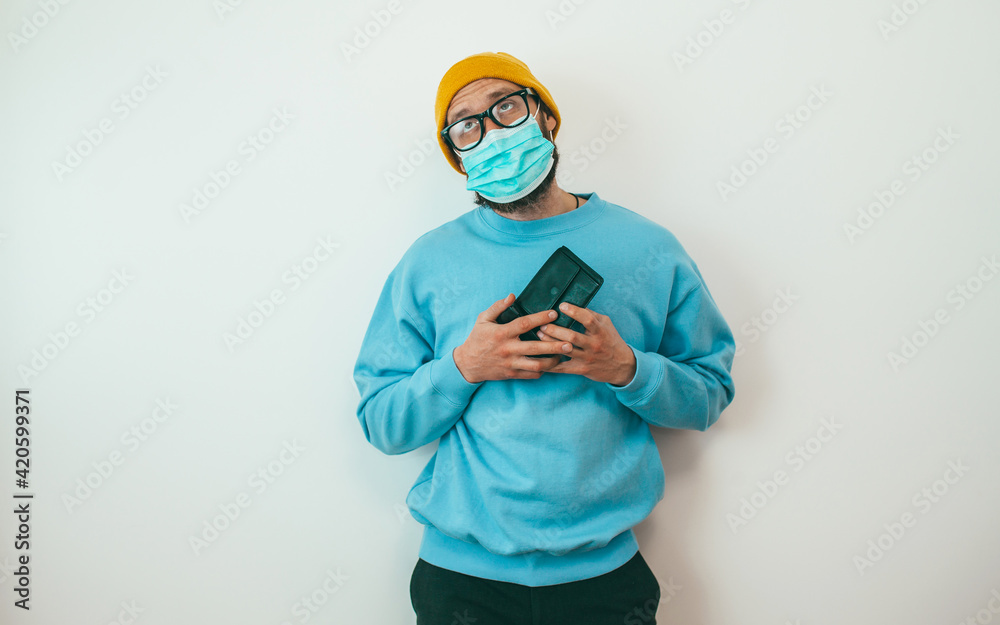 A man wearing a medical mask during quarantine or isolation due to covid, was left without work and shows an empty wallet. He has no money to live on. A man wearing a medical mask during quarantine or isolation due to covid, was left without work and shows an empty wallet. He has no money to live on.