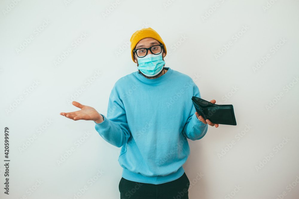 A man wearing a medical mask during quarantine or isolation due to covid, was left without work and shows an empty wallet. He has no money to live on.