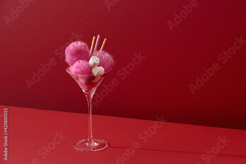 A glass of Iced strawberry shake and topped with cotton candy and marshmallow photo