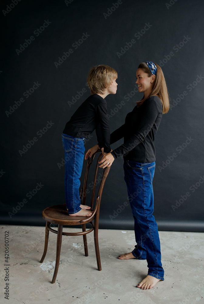 mother and son in the Studio on a black paper background in jeans and a black long sleeve jacket mother and son in the Studio on a black paper background in jeans and a black long sleeve jacket
