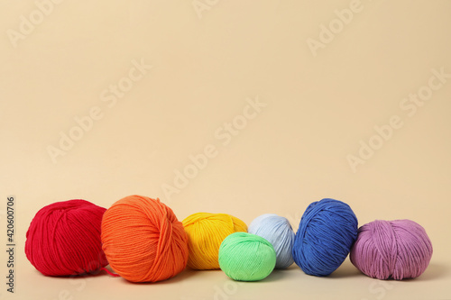 Soft colorful woolen yarns on beige background, space for text