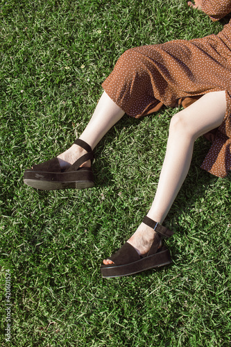 Female feet in black sandals lie on the grass photo