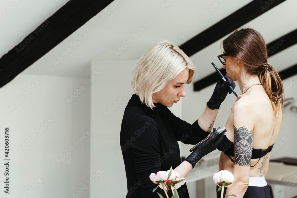 © Irina Polonina/Stocksy - Female artist in the process of making a tattoo. © Irina Polonina/Stocksy - Female artist in the process of making a tattoo.