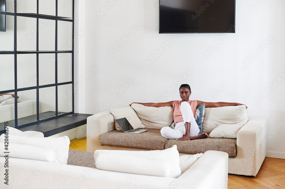 Young woman sitting on her living room sofa Young woman sitting on her living room sofa